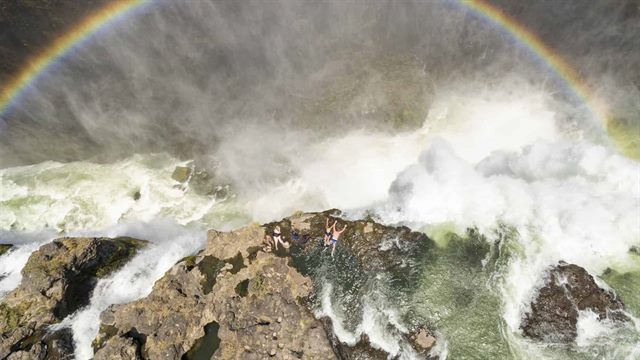 Aerial view of guests swimming at Devil's Pool, natural infinity pool at the edge of Victoria Falls